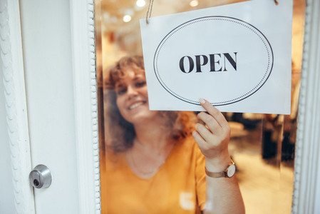 Fashion store owner hanging open sign in front door