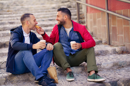 Gay couple having a take away meal on the street