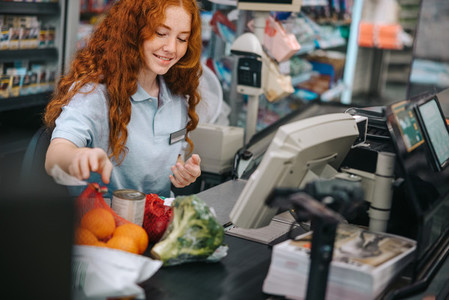 Young female working at billing counter in grocery store
