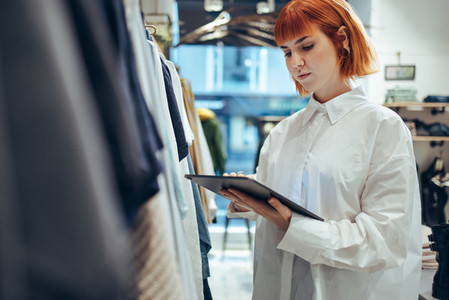 Female entrepreneur using digital tablet in her clothing store