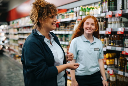 Supermarket manager training young woman worker