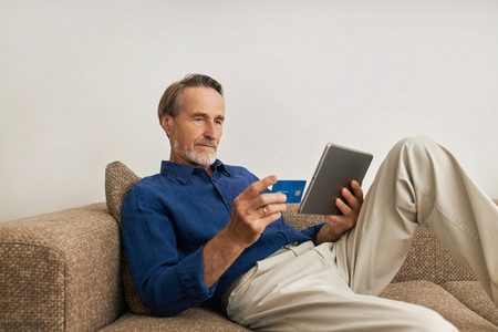 Mature man doing online payment from digital tablet