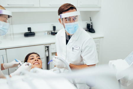 Dentist treating a female patient at dental clinic