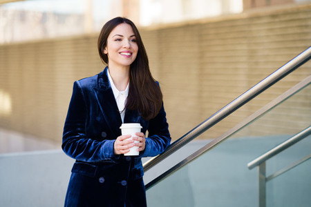 Business woman wearing blue suit taking a coffee break outside her office