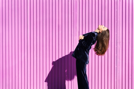 Woman wearing blue suit posing near pink shutter