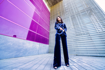 Wide angle photo of a woman wearing blue suit posing near a modern building