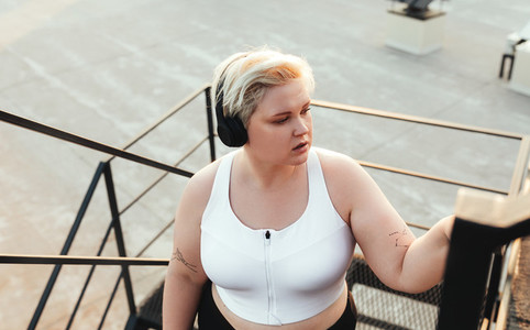 Young woman in headphones stepping up on staircase outdoors