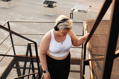 Plus size woman in sports clothes taking a break and looking down
