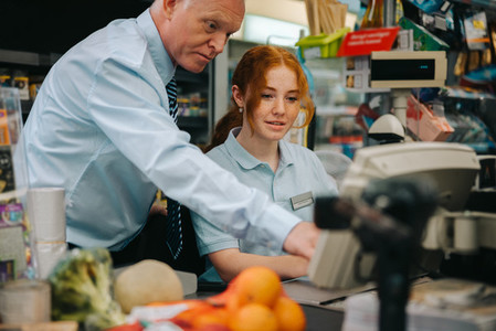 New cashier getting help from store manager at checkout
