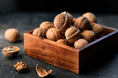 Close up of walnuts in a shell in a wooden box on a table