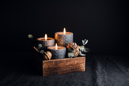 Decorations with wooden box and black burning candles in a dark interior