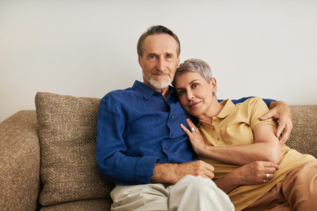 Senior couple embracing on a sofa  Affectionate people hugging at home