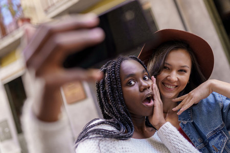 Two beautiful multiethnic women making selfie and grimacing