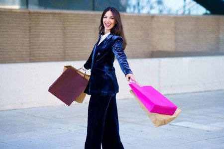Happy woman turning with joy for her purchases in shopping bags