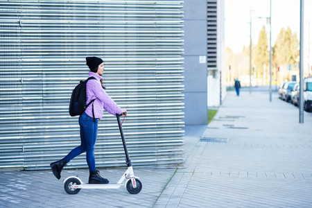 Young woman in her twenties riding an electric scooter