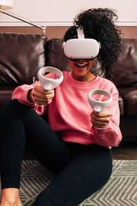 Young woman having fun and playing video games with VR set in living room