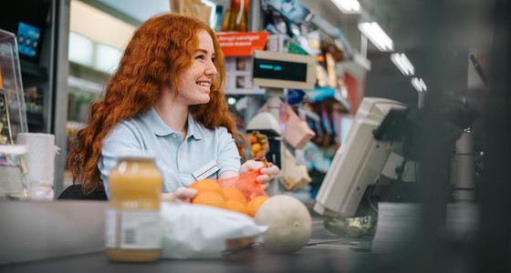 Young cashier attending customer at supermarket