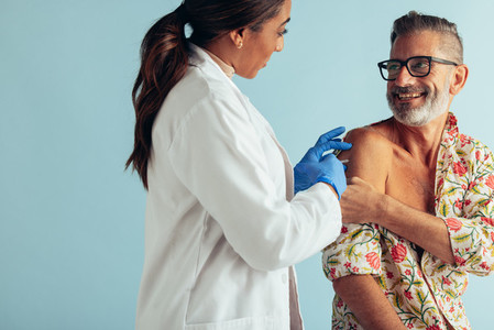 Doctor giving vaccination to mature man