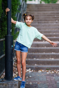 Nine year old girl standing on the steps outdoors
