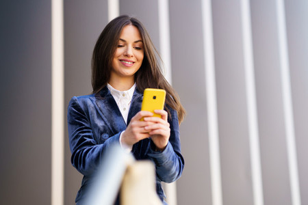 Business woman wearing blue suit using smartphone in an office building