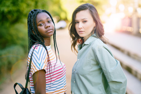 Two young friends looking at camera together on the street Multiethnic women