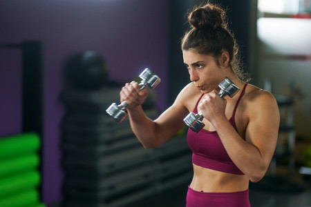 Sporty woman punching and boxing with dumbbells