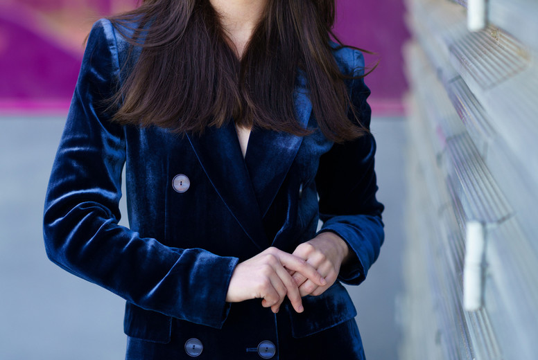 Woman wearing blue suit posing near a modern building.