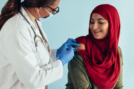 Doctor giving vaccine to muslim woman