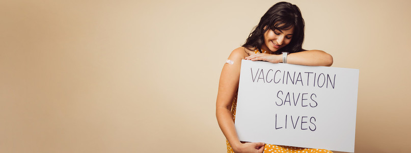 Woman holding a banner of vaccination saves lives slogan