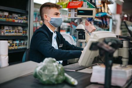 Male cashier at supermarket with face mask