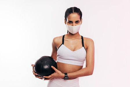 Fitness woman wearing face mask exercising with a medicine ball