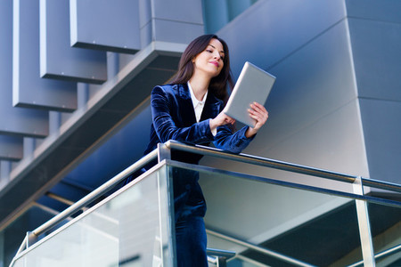 Business woman wearing blue suit using digital tablet in an office building