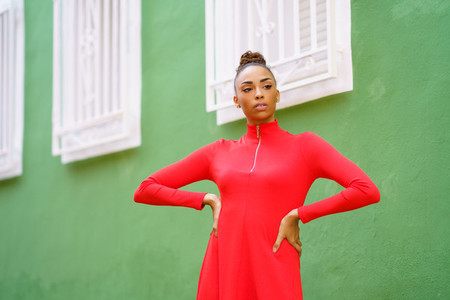Young black woman in red dress in front of a green wall
