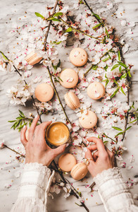 Womans hands holding fresh coffee and macaron cookies