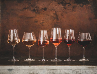 Different shades of Rose wine in glasses over brown background