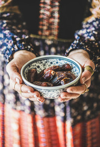 Woman in oriental dress holding bowl of dates for Ramazan