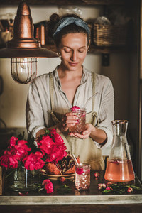 Young woman holding glass of rose homemade lemonade in hands