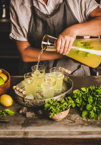 Hands of woman making fresh homemade lemonade over kitchen counter