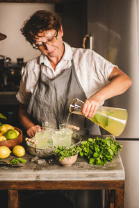 Elderly woman making fresh homemade lemonade over kitchen counter