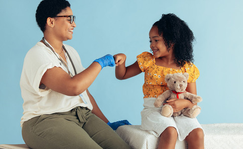 Doctor giving fist bump to girl patient