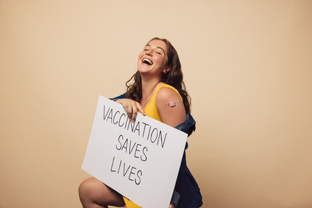 Woman laughing holding a banner of Vaccination saves lives