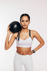 Portrait of a muscular fitness woman with a medicine ball on her shoulder