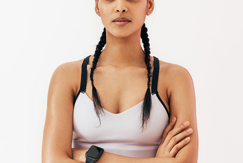 Confident fitness woman with braids standing in studio and looking at camera