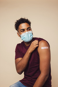 Man wearing face mask showing his vaccinated arm