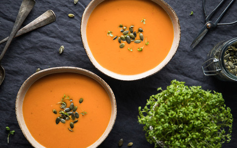 Vegetable creamy healthy soup with pumpkin seeds on a kitchen table