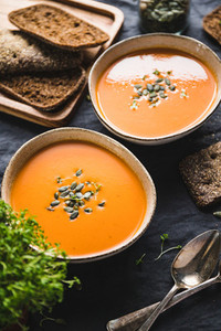 Vegetable creamy healthy soup with pumpkin seeds on a kitchen table