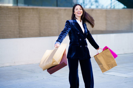 Caucasian woman turning with joy for her purchases in shopping bags
