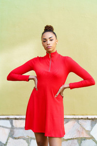 Young black woman in red dress with a serious expression in urban background