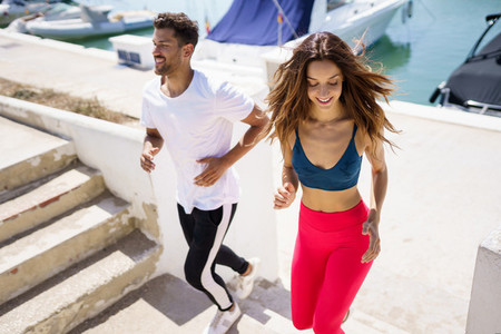 Athletic couple training hard by running up stairs together outdoors