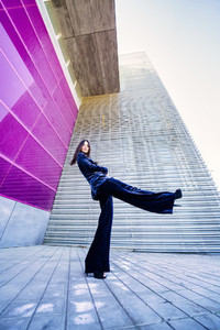 Wide angle photo of a woman wearing blue suit posing near a modern building